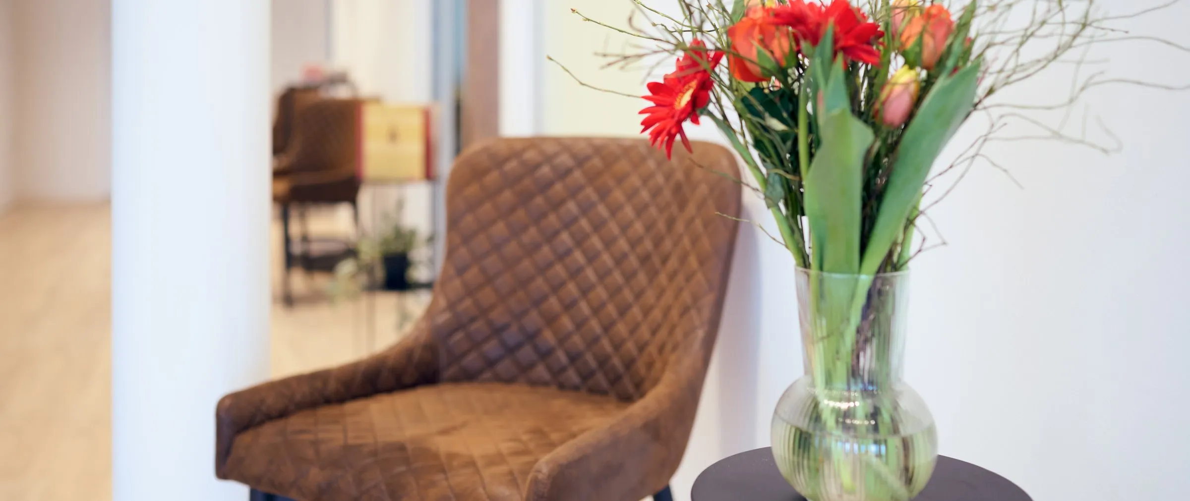 Wartebereich mit Ledersessel und Blumen